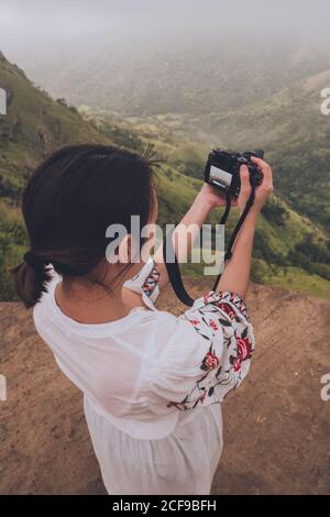 Einsame Frau mit Kamera in den Händen auf nebligen Hügeln Stockfoto