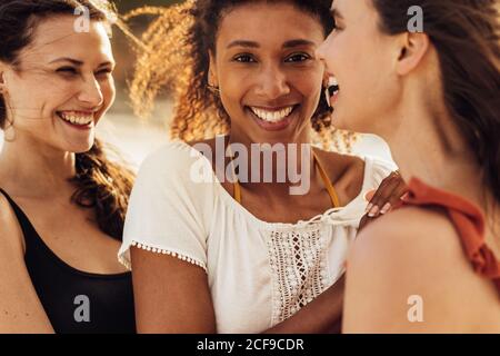 Nahaufnahme von drei Freundinnen, die im Freien stehen. Eine kurze Aufnahme multiethnischer Freundinnen, die zusammen stehen und lachen. Stockfoto