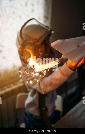 Fantasizing Junge in Astronaut Helm spielen mit Papier Flugzeug an Zu Hause Stockfoto