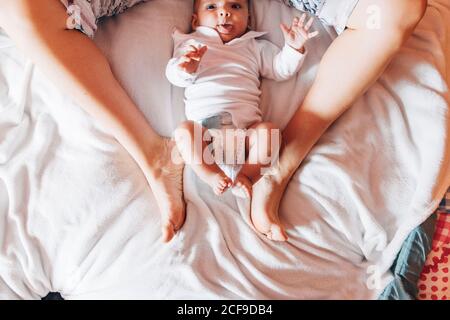 Draufsicht auf Ernte neugeborenes Baby in Windel liegend auf Bett mit Mutter im Haus Stockfoto