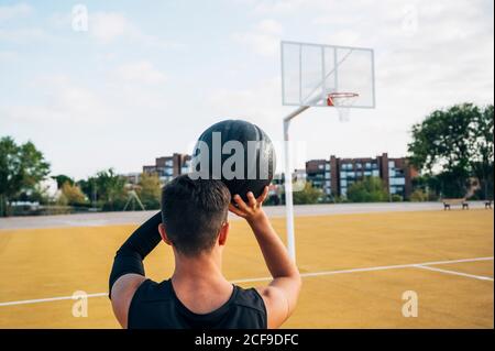 Junger Mann, der draußen auf dem Basketballplatz spielt. Stockfoto