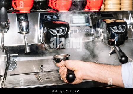 Von oben anonymer Barista, der im Stehen aromatischen Kaffee zubereitet In der Nähe professionelle Kaffeemaschine mit Portafilter im Café Stockfoto