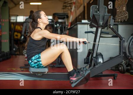 Starke Frau, die im Fitnessstudio am Gerät trainiert Stockfoto