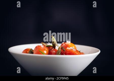 Frische Kirschtomaten mit grünem Spargel und Rosmarin anbraten Stockfoto