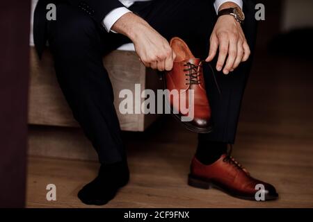 Geschäftsmann, der sich auf die Arbeit vorbereitet. Der Mann zieht seine braunen Schuhe an. Stockfoto