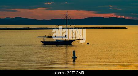 Segelboot liegt am Ufer des Lake Champlain in Vermont Wie die Sonnenuntergänge hinter den Adirondack Mountains in New York Auf der anderen Seite des Sees Stockfoto