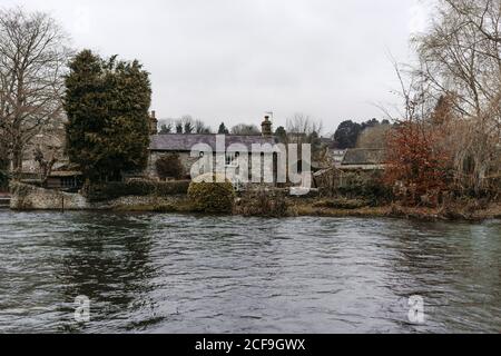 Ruhige ruhige Landschaft des Flussufers mit üppigen Pflanzen und Altes Haus und Fluss fließen in grauen Tag in vereint Königreich Stockfoto