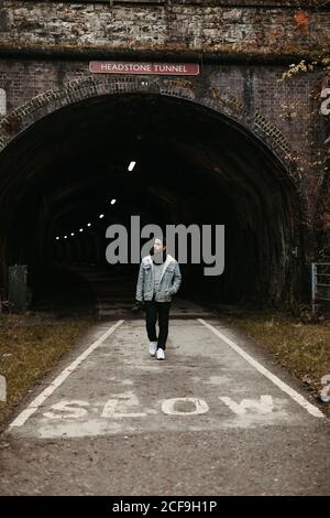 Mann, der auf der Straße vor einem dunklen Tunnel läuft Stockfoto