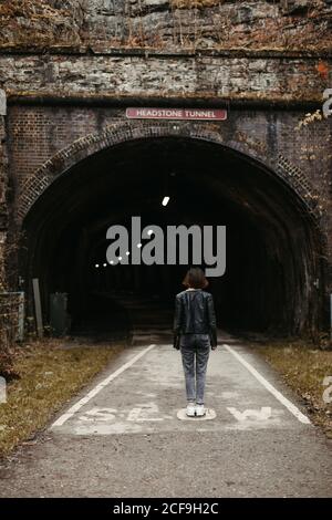 Frau, die vor einem dunklen Tunnel auf der Straße steht Stockfoto