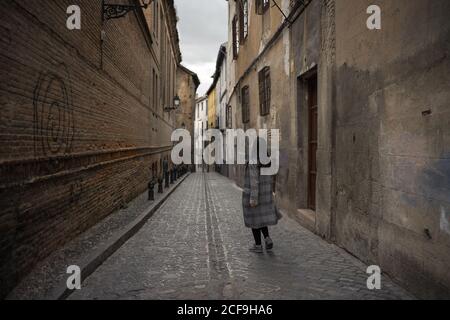 Frau, die auf einer alten leeren Gasse mit alten Gebäuden läuft Stockfoto