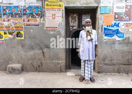 Bangladesch - Januar, 25 2019: Ältere ethnische Männer in traditioneller Kopfbedeckung lächeln und schauen auf die Kamera auf der Straße Stockfoto