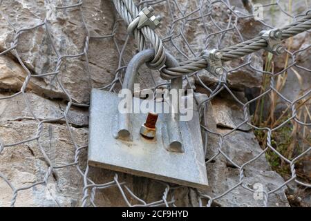 Nahaufnahme der Metallkabel ist auf dem Felsen fixiert. Stockfoto