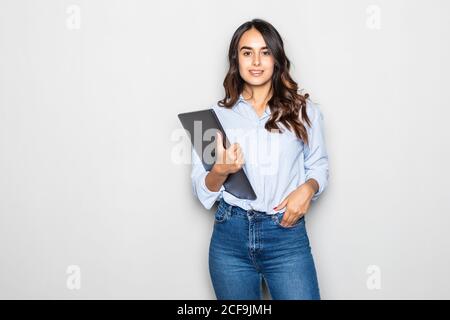 Glückliches Mädchen hält Laptop und Blick auf Kamera über grau Hintergrund Stockfoto