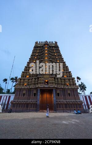 Jaffna, Sri Lanka - 7. August 2019: Außenansicht von ornamentalen Gopuram Turm mit Laternen gegen Abendhimmel während Nallur Kandaswamy Kovil Festival beleuchtet Stockfoto