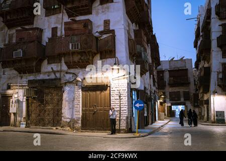 Typische Wohngebäude aus Stein mit schäbigen Wänden und Balkonen Alte Straße von Jeddah Stadt in Saudi-Arabien in der Nacht Zeit mit Menschen zu Fuß Stockfoto