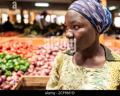 Jinja, Uganda - September 30: Frau steht auf einem großen Gemüse- und Obstmarkt mit Reihen Stockfoto