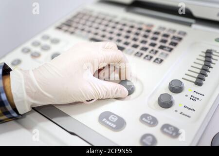 Erntegut Hand des professionellen Arztes in Schutzhandschuhe Einrichtung Diagnosegeräten während der Untersuchung des Patienten in der Klinik Stockfoto
