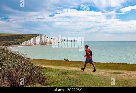 Seaford UK 04 September 2020 - EIN Spaziergänger genießt heute warmes, sonniges Wetter mit einer Mischung aus Wolken auf den Klippen, die Cuckmere Haven und die Seven Sisters in der Nähe von Seaford an der Sussex-Küste überblicken. : Credit Simon Dack / Alamy Live News Stockfoto