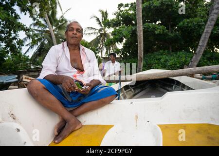 Tangalle, Sri Lanka - 28. Juli 2019: Von oben von gesichtslosen ethnischen Mann in Casual tragen demonstriert Betelnuss auf grünem Blatt Stockfoto