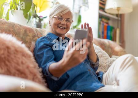 Ältere Frau mit Handy zu Hause Stockfoto