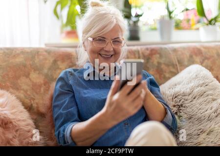 Ältere Frau mit Handy zu Hause Stockfoto