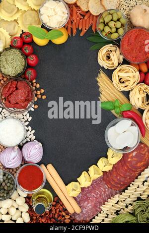 Mediterranean & Italian Health Food cholesterinarme Ernährung mit Salami, Pasta, Saucen, Tomaten, Gemüse. Hintergrund Rand auf Schiefer. Stockfoto