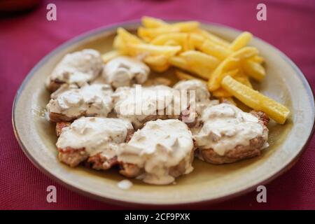 Teller mit Pommes Frites mit Fleisch in Sauce im Restaurant Stockfoto