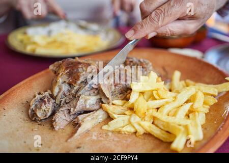 Gesichtslose Frau, die im Restaurant Pommes mit Fleisch in Sauce isst Stockfoto