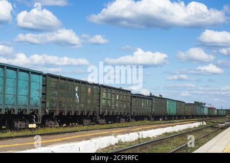 Ein Güterzug steht auf den Gleisen gegen ein Hintergrund von blauem Himmel und Wolken Stockfoto