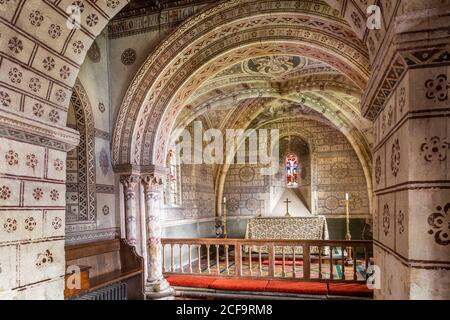 Die normannische Kirche St. George im Cotswold-Dorf Hampnet zeigt den Chor aus dem 12. Jahrhundert, der in den 1870er Jahren vom damaligen Vikar dekoriert wurde. Stockfoto