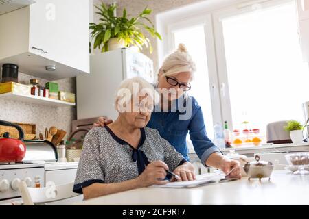 Ältere Frau hilft älteren Mutter mit Papierkram Stockfoto