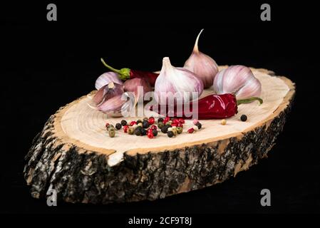 Knoblauch, Paprika und bunte Pfefferkörner auf Holzhintergrund. Nahaufnahme von Gewürzen und Gewürzen. Low-Taste Stockfoto