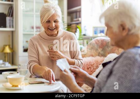 Ältere Frau und ihre Erwachsene Tochter spielen Karten zu Hause Stockfoto