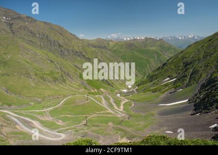 Von oben herrlicher Blick auf leere Serpentinenstraße auf grün Grashang gegen nebeliges Tal und bewaldete Berge in Georgien Stockfoto