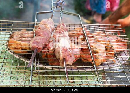 Spieße mit Schweinefleisch auf Grill mit mariniertem Huhn Die Stücke auf der Platte schließen sich auf dem schmutzigen Tisch im Freien an Dorf am Sommertag Stockfoto