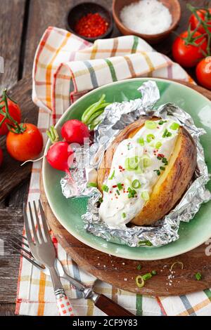 Gebackene Kartoffel mit Sauerrahm und frischen Kräutern Stockfoto