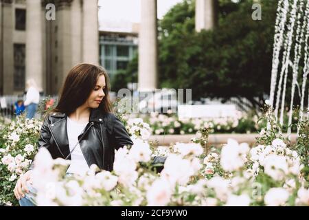 Junge Frau mit langen Haaren in der Straße einer Großstadt, umgeben von Rosen. Sankt Petersburg, Russland. Stockfoto