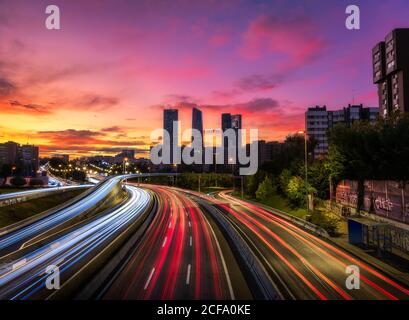 Drohne Ansicht der Stadtlandschaft mit leuchtenden Autobahn in Langzeitbelichtung Und Wolkenkratzer unter Sonnenuntergang Himmel Stockfoto