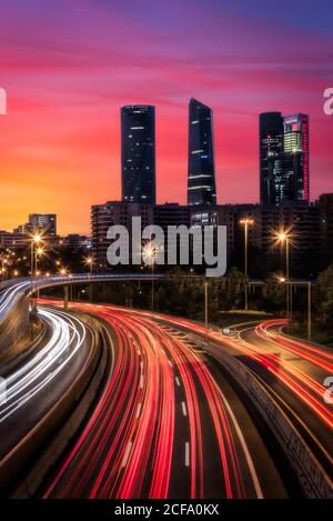 Drohne Ansicht der Stadtlandschaft mit leuchtenden Autobahn in Langzeitbelichtung Und Wolkenkratzer unter Sonnenuntergang Himmel Stockfoto