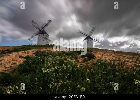 Von unten alte traditionelle Windmühlen auf dem Hügel gelegen An bewölktem Tag auf dem Land Stockfoto