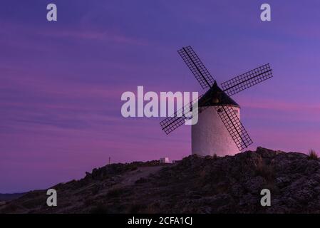 Alte Windmühle auf einer felsigen Klippe gegen bewölkten Sonnenuntergang Himmel auf dem Land Stockfoto