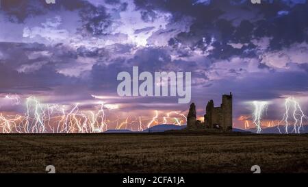 Erstaunliche Landschaft von Gewitter auf bunten bewölkten Himmel über Alte Burg bei Nacht ruiniert Stockfoto