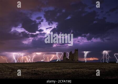 Erstaunliche Landschaft von Gewitter auf bunten bewölkten Himmel über Alte Burg bei Nacht ruiniert Stockfoto