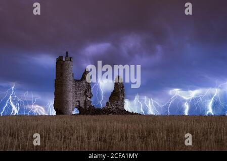 Erstaunliche Landschaft von Gewitter auf bunten bewölkten Himmel über Alte Burg bei Nacht ruiniert Stockfoto