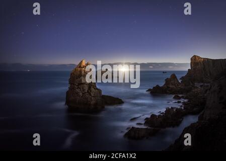 Erstaunliche Seestück der rauhen felsigen Küste des Meeres mit Sonnenuntergang Sonne und Himmel mit Sternen Stockfoto