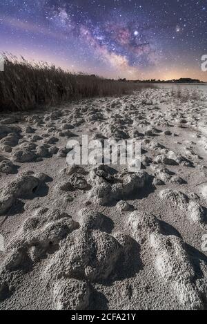 Trockenheit Wüstenlandschaft mit trockenem Boden und Pflanzen unter bunten Nahe am Himmel mit milchiger Straße Stockfoto