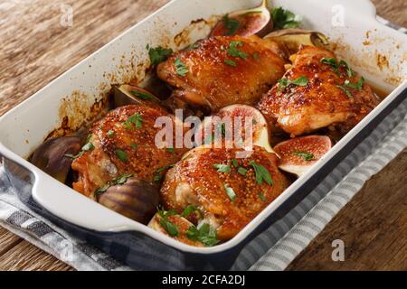 Gebackene Hähnchenschenkel mit Feigen und Kräutern Nahaufnahme in einer Auflaufform auf dem Tisch. Horizontal Stockfoto
