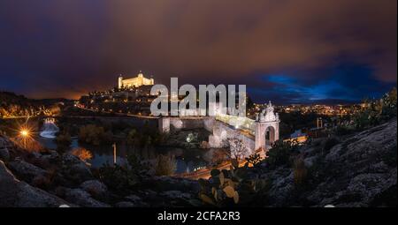 Wundervolle Landschaft des beleuchteten alten Palastes, der über der Stadt in gebaut wurde Bunte Nacht in Toledo Stockfoto