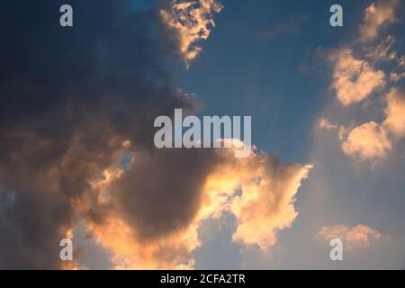Dramatisch bedeckter Himmel mit den Strahlen der Sonne, in gelben und blauen Farben, Hintergrundbild. Stockfoto