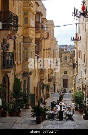 Die historische Kirche St. Lucy befindet sich am Fuße einer Fußgängerzone der St. Lucia Straße mit Geschäften und Restaurants in Valletta, Malta gesäumt. Stockfoto